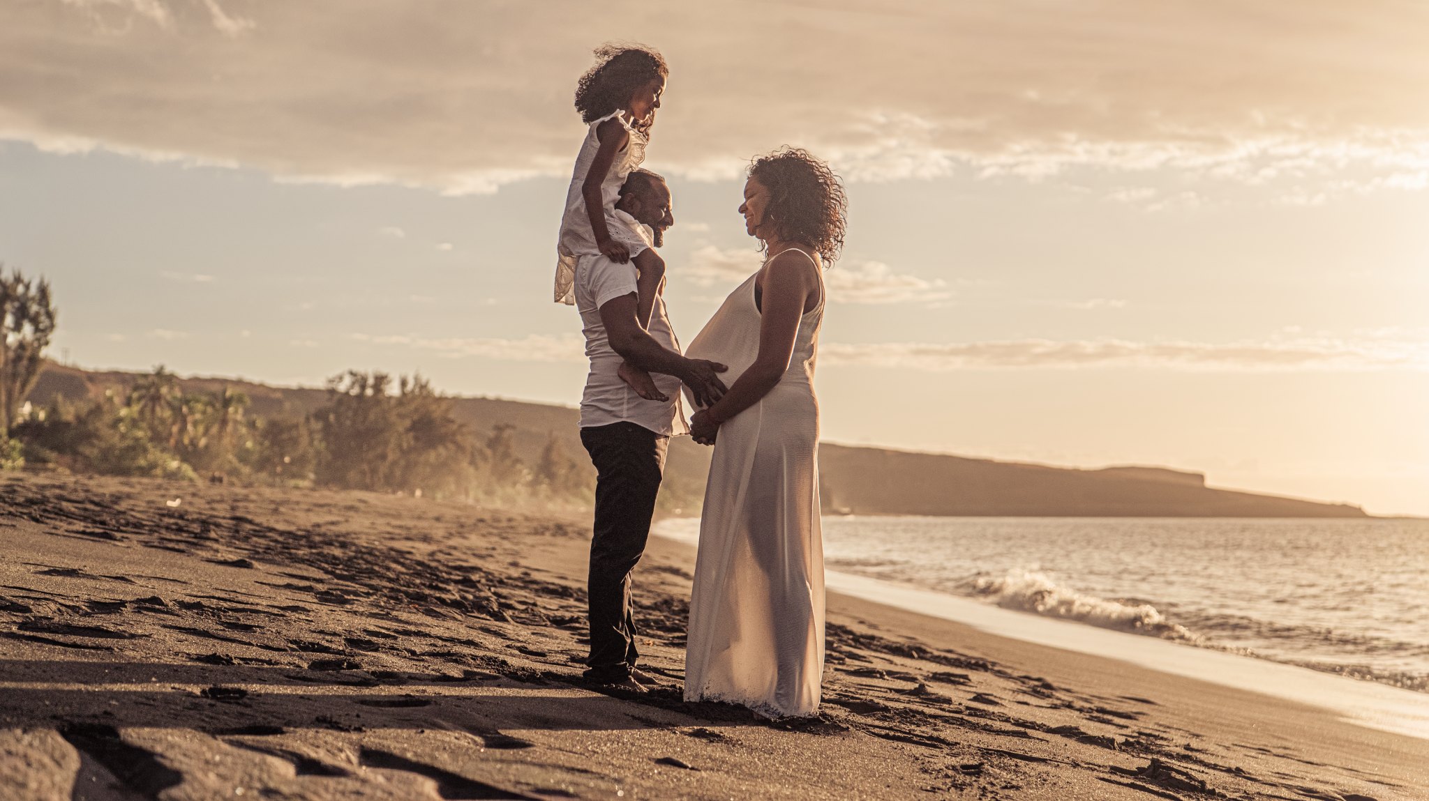 Famille lors d'une séance grossesse au coucher du soleil